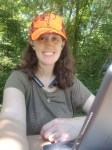 Author Ashley Crookham writing in the woods